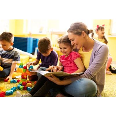 Happy little girl sitting in teacher's lap in kindergarten and reading a book while the other children are playing. (Happy little girl sitting in teacher's lap in kindergarten and reading a book while the other children are playing., ASCII, 116 compon
